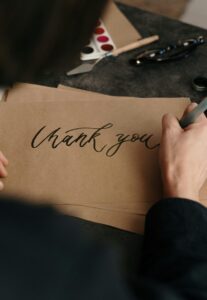 Person writing a 'Thank You' card with calligraphy. Perfect for gratitude expressions.