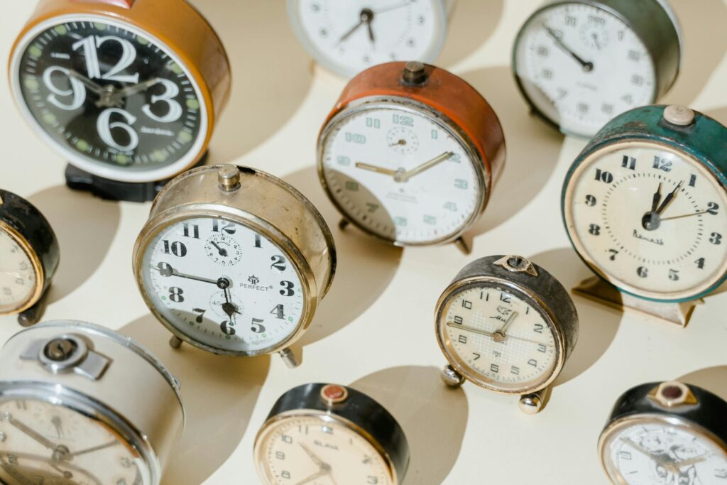 A collection of retro alarm clocks set against a sunny background, showcasing vintage design.