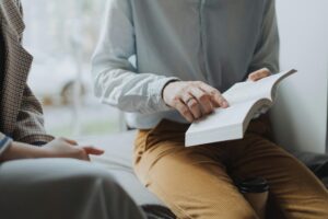 A cozy indoor reading session with two adults discussing a book, providing a relaxed atmosphere.