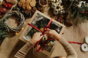 Top view of a Christmas gift wrapping scene with cookies, baubles, and festive decorations.